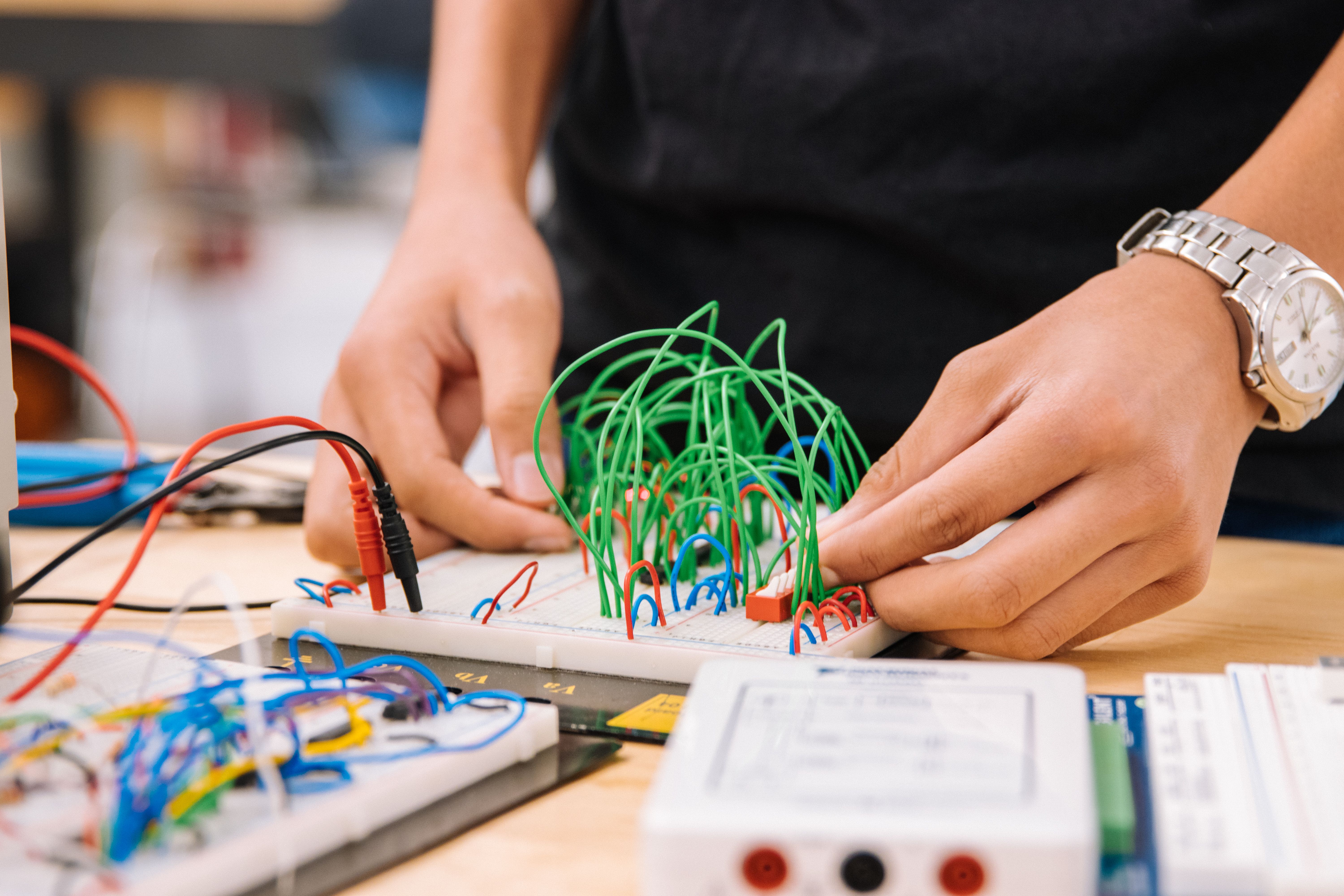 Hands manipulating wires on breadboards during an electronics prototyping project