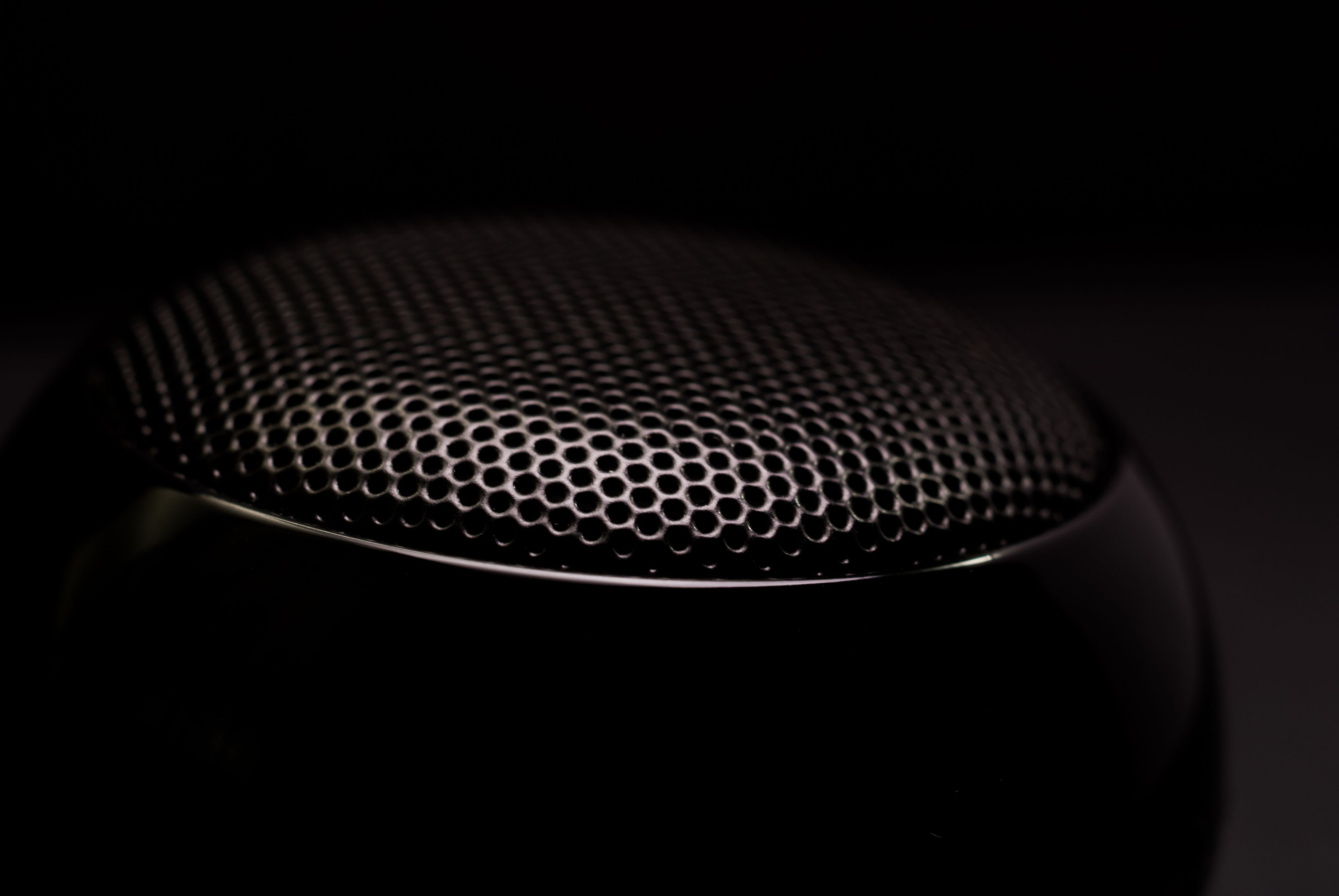 Close-up of a black speaker grille showing the texture and structure of a small audio speaker
